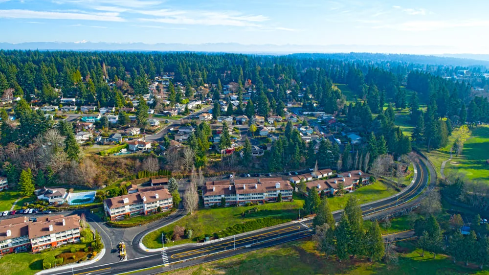 Aerial view of a residential neighborhood, condominiums and a freshly striped road surrounded by evergreen trees near Airway Heights, WA