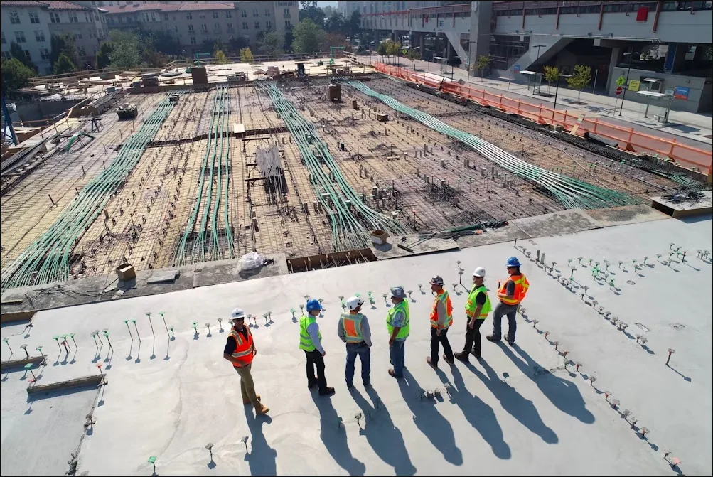 Project team in hard hats and safety vests walking a large commercial construction site, representing commercial paving coordination in Spokane, WA
