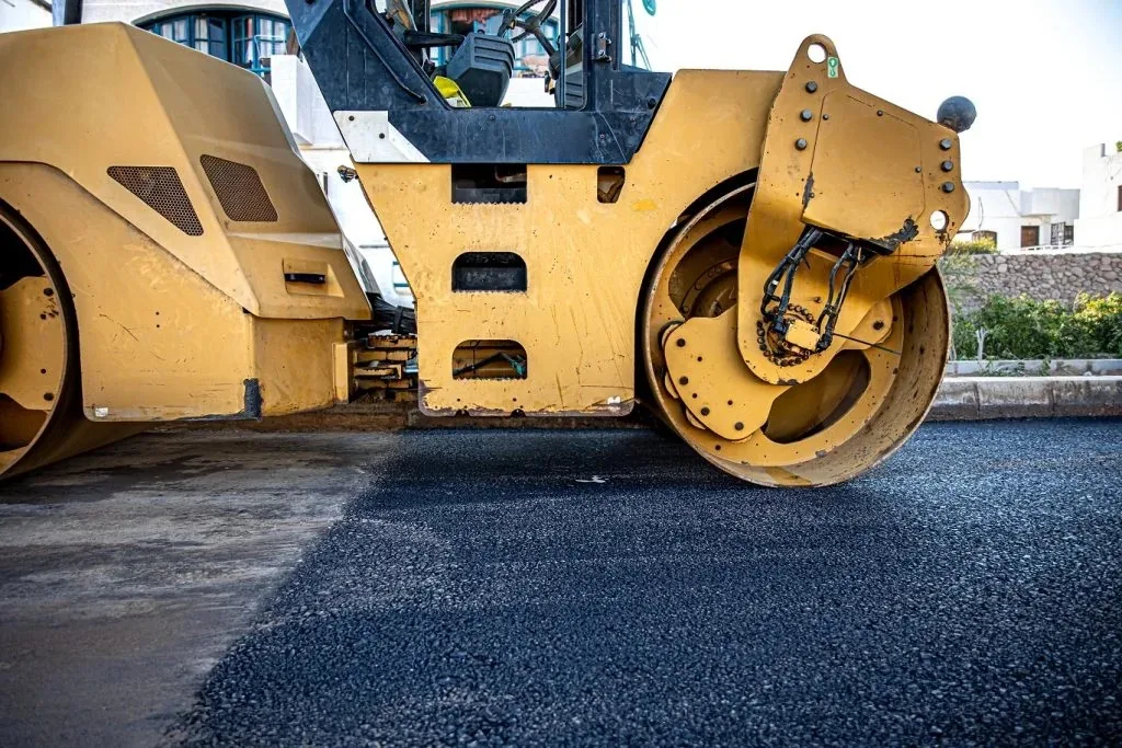 Vibratory roller compacting fresh hot-mix asphalt during commercial paving in Spokane, WA