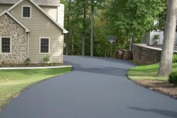 Smooth, freshly sealed black asphalt driveway curving past a stone and siding home, an example of residential paving in Spokane, WA