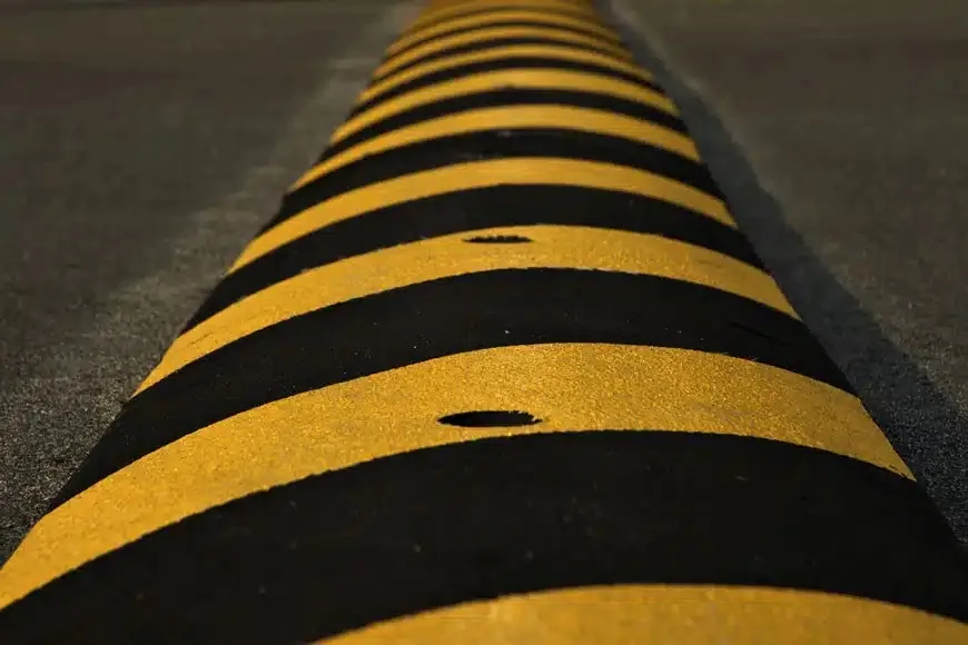 Close-up of an asphalt speed bump with yellow and black striping, an example of speed bump installation in Spokane, WA