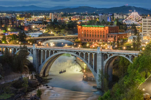 Historic bridge and Washington Water Power building lit at dusk above the Spokane River falls in downtown Spokane, WA
